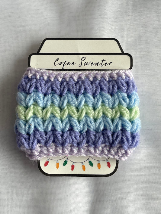 Crocheted coffee sleeve with multicolor pattern on a gray background